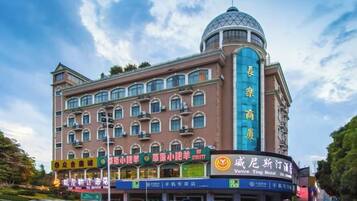 A multi-story hotel with a prominent dome on the top, multiple balconies, and a variety of signage indicating different services and amenities.