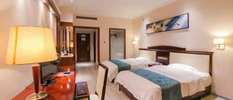 A hotel room with two beds, a desk with a lamp, a chair, and a painting on the wall.