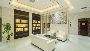 A modern lobby with a white sofa, a glass coffee table, and a bookshelf. - Baise Changle Business Hotel (Baise)