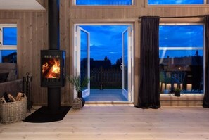 A cozy room with a wood-burning stove, a large window, and a view of the outside. - Modernt, Barnvänligt Boende 1 h fr Oslo i Norges Toscana. Skidparadis fin Natur (Innlandet)