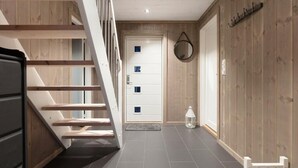 Un interior moderno con una escalera de madera, una puerta blanca con pequeñas ventanas y un farol en el suelo.