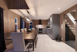 A modern kitchen with wooden cabinetry, a dining area with a long table and chairs, and a staircase leading to an upper level. - Modernt, Barnvänligt Boende 1 h fr Oslo i Norges Toscana. Skidparadis fin Natur (Innlandet)