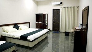Una habitación de hotel con cama, armario, escritorio y aire acondicionado.