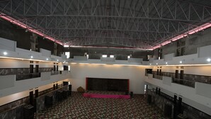 Un espacio interior con techo alto, piso estampado y una zona central para escenario.