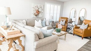 A living room with a sofa, armchairs, a coffee table, and a side table with a lamp.
