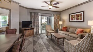 A hotel room with a television, a sofa, a chair, a dining table, and a ceiling fan. - Discover the Heart of Music City at Wyndham Nashville – 2 Bd. Dxl-Family Getaway (Nashville)