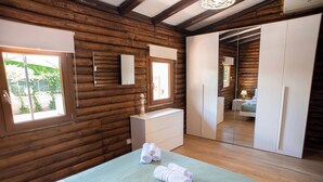 A wooden cabin-style bedroom with a bed, a dresser, a mirror, and a closet.