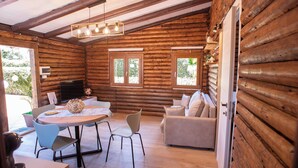 A log cabin with a dining area, sofa, and a television.