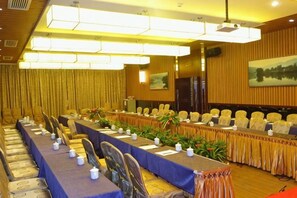 Un salón de conferencias con una larga mesa, sillas y una pantalla para proyector.