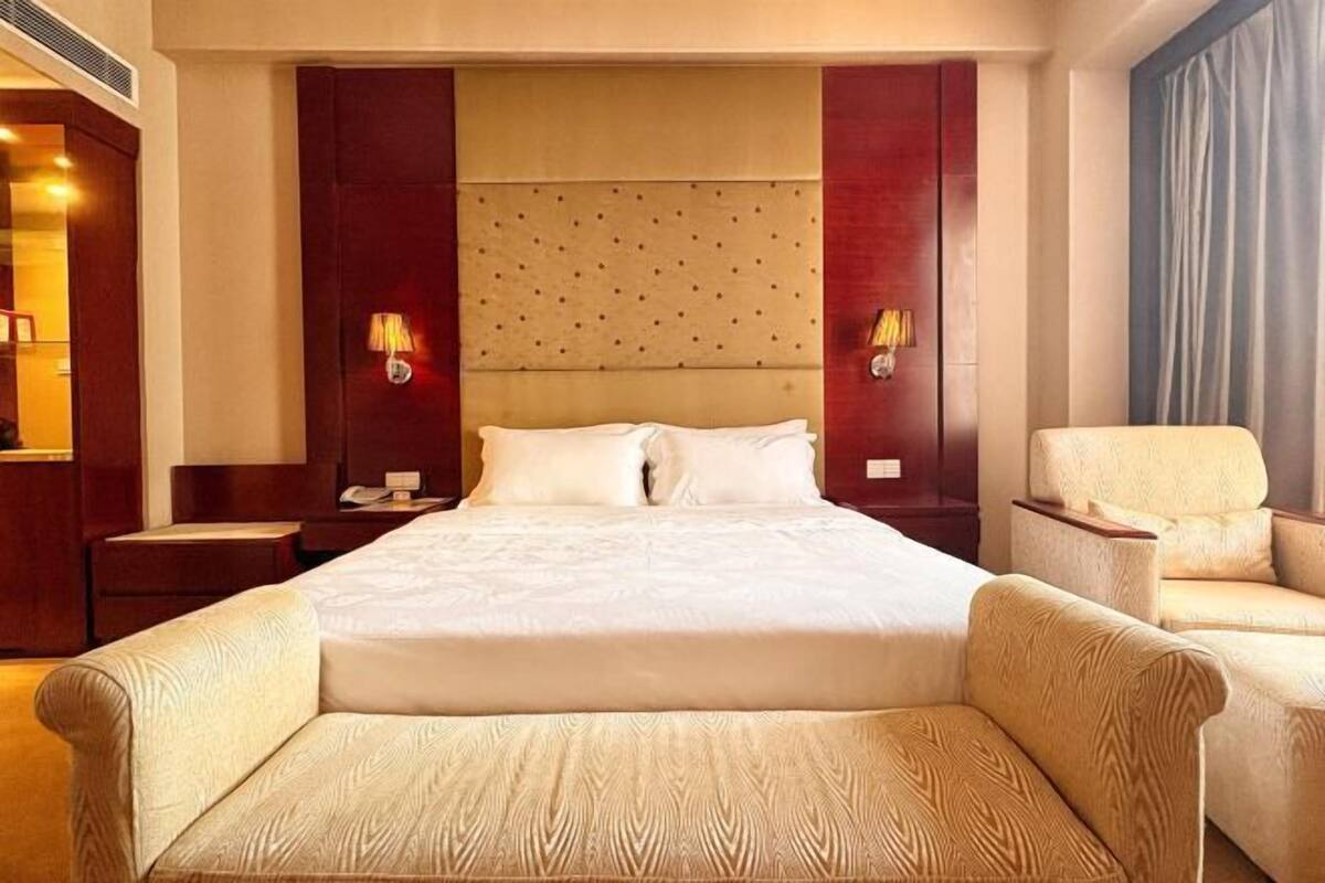 A hotel room with a large bed, two bedside lamps, a chair, and a nightstand.