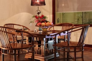 Una mesa de comedor con cuatro sillas de madera, un jarrón con flores y una lámpara.