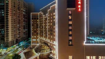 Un edificio de hotel de varios pisos con un letrero rojo llamativo en la fachada, rodeado de otros edificios altos.