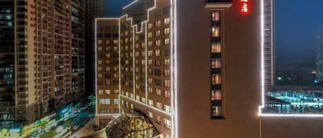Un edificio de hotel de varios pisos con un letrero rojo llamativo en la fachada, rodeado de otros edificios altos.