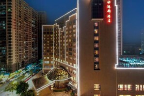 A multi-story hotel building with a prominent red sign on the facade, surrounded by other high-rise buildings. - Ruijin Hotel (Dabu)
