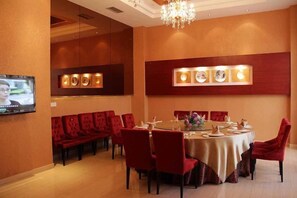 A dining area with a round table, red chairs, and a chandelier.