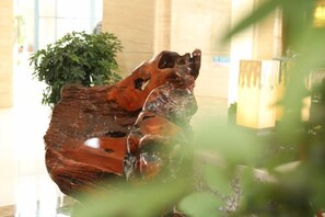 A wooden sculpture in a lobby area with a plant in the background. - Ruijin Hotel (Dabu)