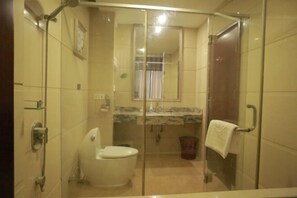 A bathroom with a glass-enclosed shower, a toilet, a sink with a mirror, and a towel rack. - Ruijin Hotel (Dabu)
