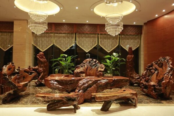 A lobby with a central wooden sculpture, chandeliers, and patterned curtains. - Ruijin Hotel (Dabu)