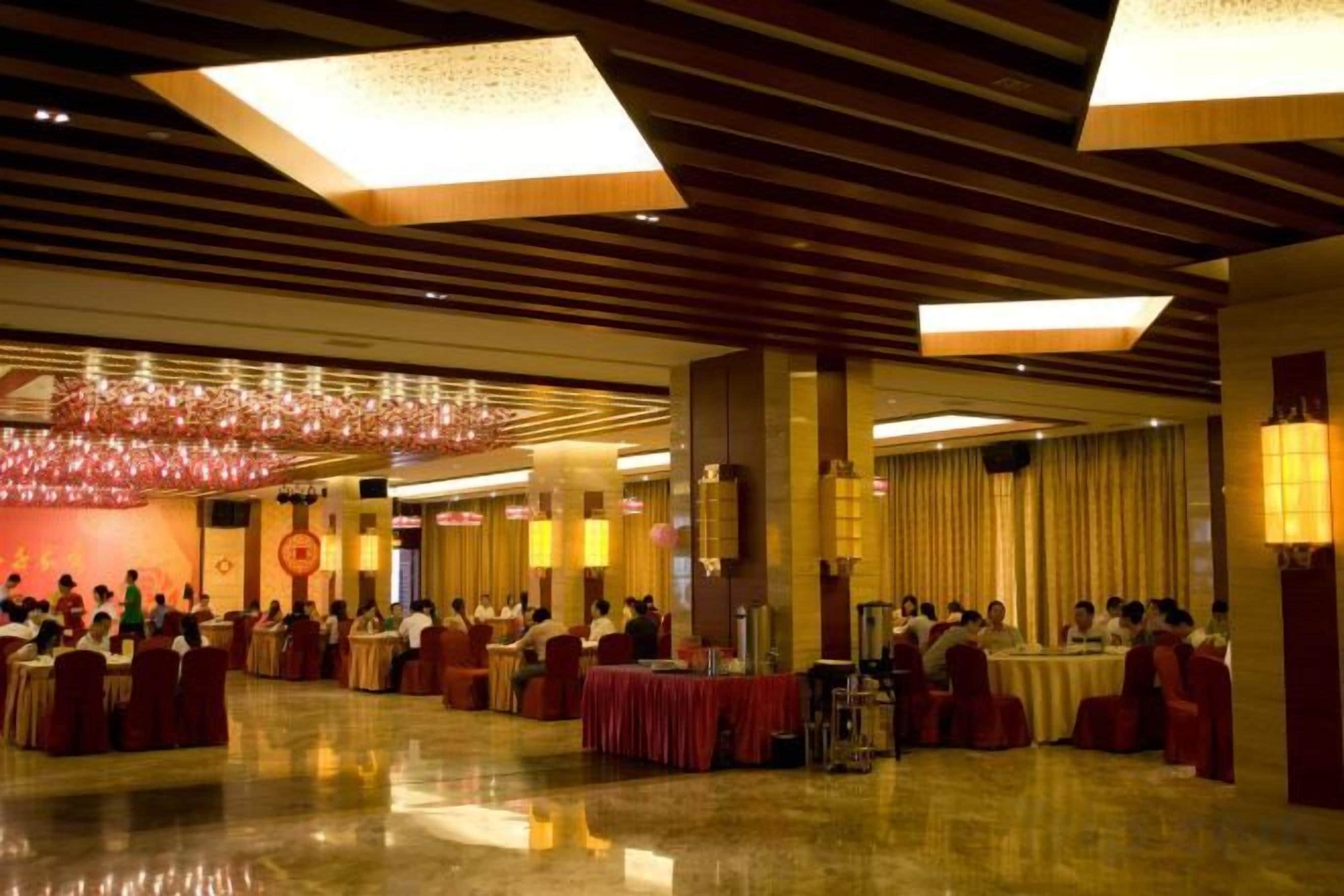 Une vaste salle de banquet dotée de hauts plafonds et de lustres, avec des tables dressées pour un événement formel.