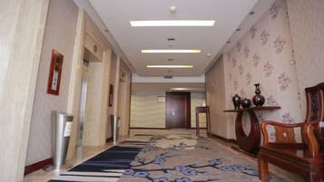 A hotel corridor with a carpet, a reception desk, and a wooden chair.