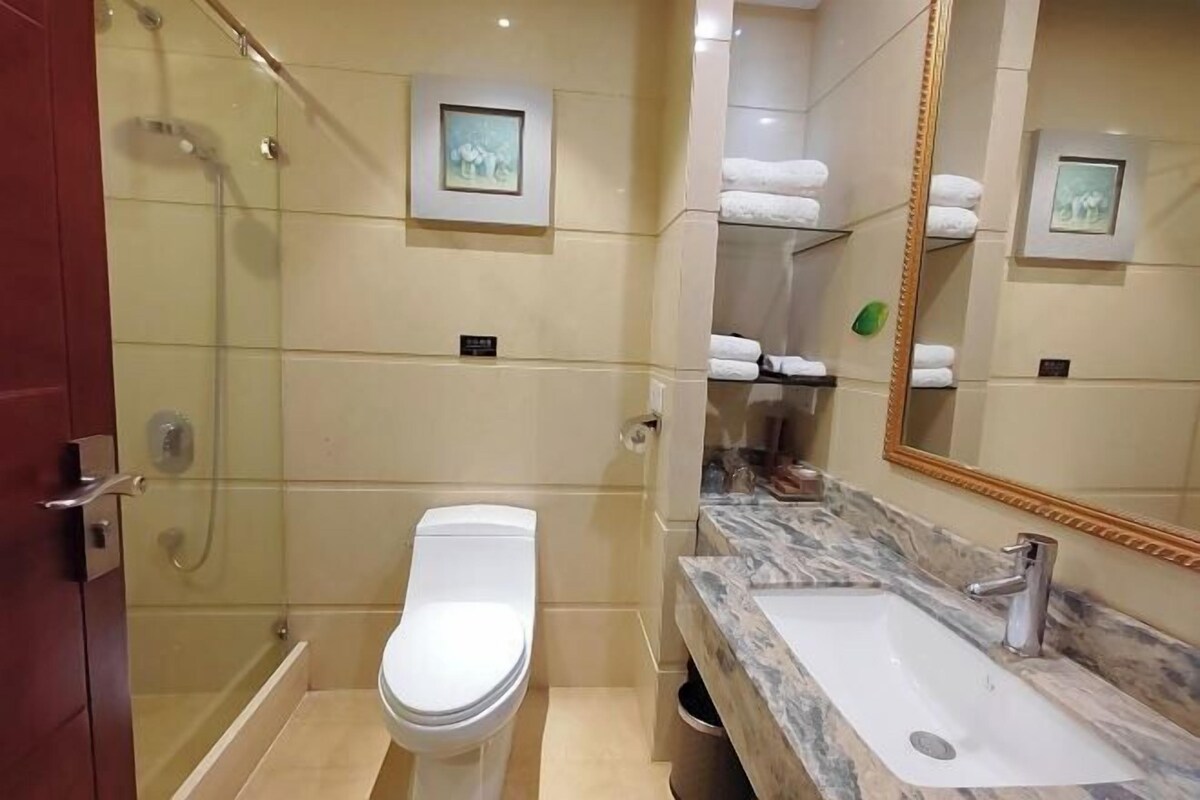 A bathroom with a glass-enclosed shower, a white toilet, a marble sink, and a large mirror.
