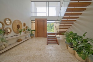 A modern interior with a wooden staircase, a large wooden door, and decorative wall mirrors. - Modern Lake Villa With English Speaking Staff in Golf and Beach Resort (Punta Cana)