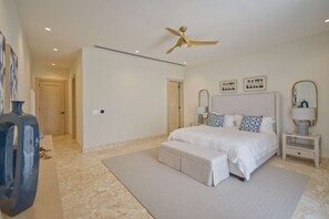 A bedroom with a bed, a nightstand, a mirror, a ceiling fan, and a large window. - Modern Lake Villa With English Speaking Staff in Golf and Beach Resort (Punta Cana)