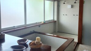 Un baño con bañera, ducha y ventana. Hay vigas de madera en el techo y un perchero en la pared.