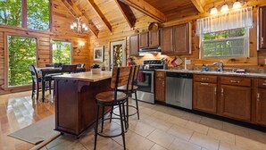 Una cocina amplia con armarios de madera, una isla grande con taburetes de bar y vistas al exterior a través de ventanas grandes.