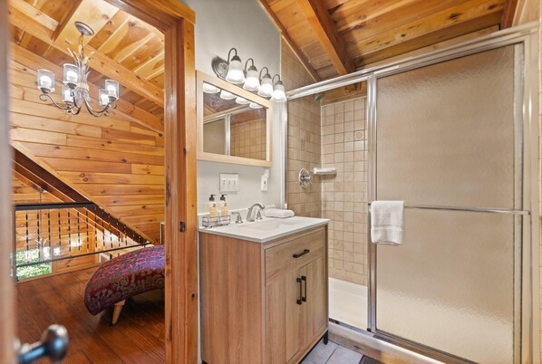 Un intérieur en bois avec une salle de bain comprenant une douche à parois de verre, un lavabo et un miroir.