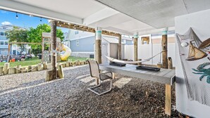 A covered outdoor seating area with a table and chairs, a hammock, and a playground in the background. - Seas the Moment - 1 Blk to Ortley Beach - Private Balcony & Patio - 6 Bed, 3 BR (Seaside Heights)