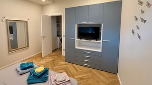 Een slaapkamer met een grote garderobe, een flatscreen televisie en een bed met opgevouwen handdoeken.