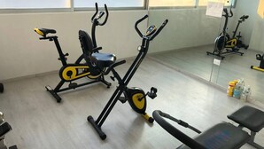 Een sportschool met twee hometrainers, een bank en een spiegel die de fietsen weerspiegelt.