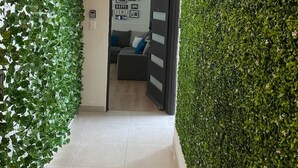 Een gang met een groene muur en een deur die leidt naar een woonruimte met een bank en een muur met ingelijste foto's.