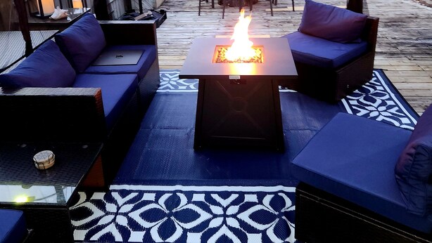An outdoor patio with a fire pit, seating, and a table.