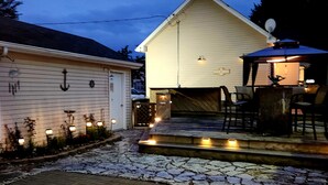 A two-story house with a porch, a satellite dish, and outdoor lighting.