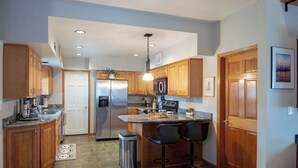A modern kitchen with wooden cabinets, stainless steel appliances, and a central island with bar stools.