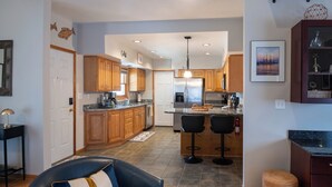 A modern kitchen with wooden cabinets, a central island with bar stools, and a stainless steel refrigerator.