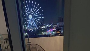 A balcony with two wicker chairs and a small table, overlooking a cityscape with a brightly lit Ferris wheel. - NEW Penthouse for 8 in La Estrella de Puebla (Heroica Puebla de Zaragoza)