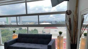 A modern living room with a dark sofa, large windows, and decorative plants. - NEW Penthouse for 8 in La Estrella de Puebla (Heroica Puebla de Zaragoza)