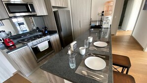 Una cocina moderna con una isla central, electrodomésticos de acero inoxidable y suelo de madera.