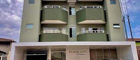 A building with the sign 'ELDORADO Economic' on the facade, featuring a modern design with balconies and a garage entrance.