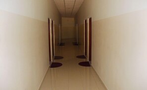 Um corredor estreito com duas portas de cada lado, que dá para um quarto.
