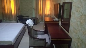 A hotel room with a bed, a desk, a chair, a mirror, and curtains. - Sultanate Suites GRA Kano (Kano)