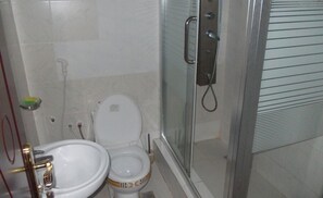 Casa de banho com sanita, lavatório e chuveiro.