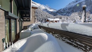 Un balcón cubierto de nieve con vistas a una cordillera.