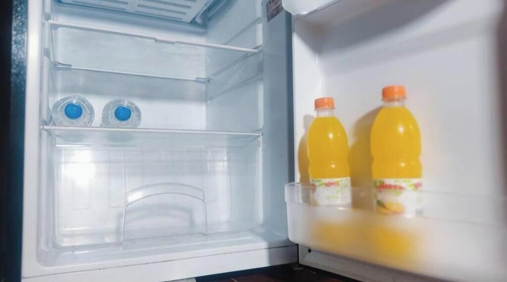 An open refrigerator with two bottles of orange juice and two bottles of water.