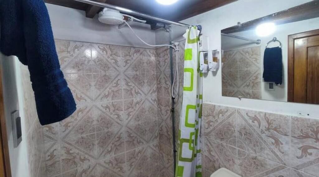 A bathroom with patterned tiles, a shower curtain, a towel rack, and a mirror.