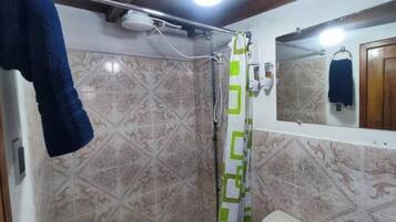 A bathroom with patterned tiles, a shower curtain, a towel rack, and a mirror.