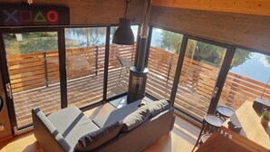 Ein modernes Zimmer mit einer Couch, einem Tisch und einem großen Fenster mit Blick auf eine Holzterrasse.